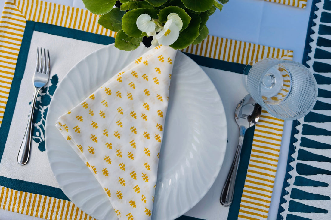 a summer tablescape for a popup market in Toronto featuring mustard & blue placemat and a cotton napkin with mini motifs in mustard. 
