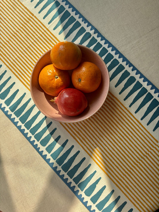 Blue & Mustard table runner with a centerpiece of a bowl of fruits on a solid beige tablecloth