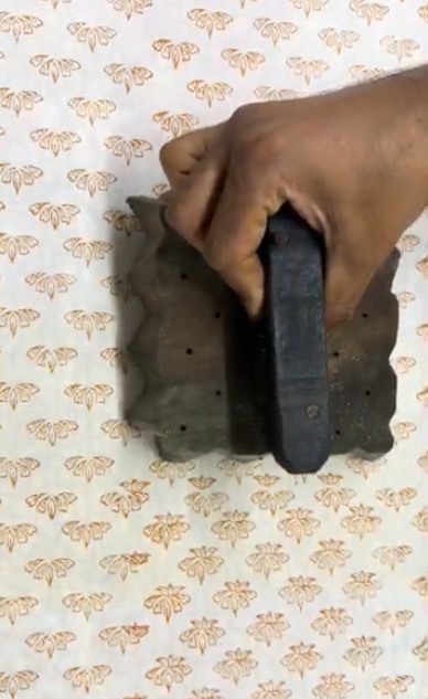 wooden block being pressed onto a floral terracotta print